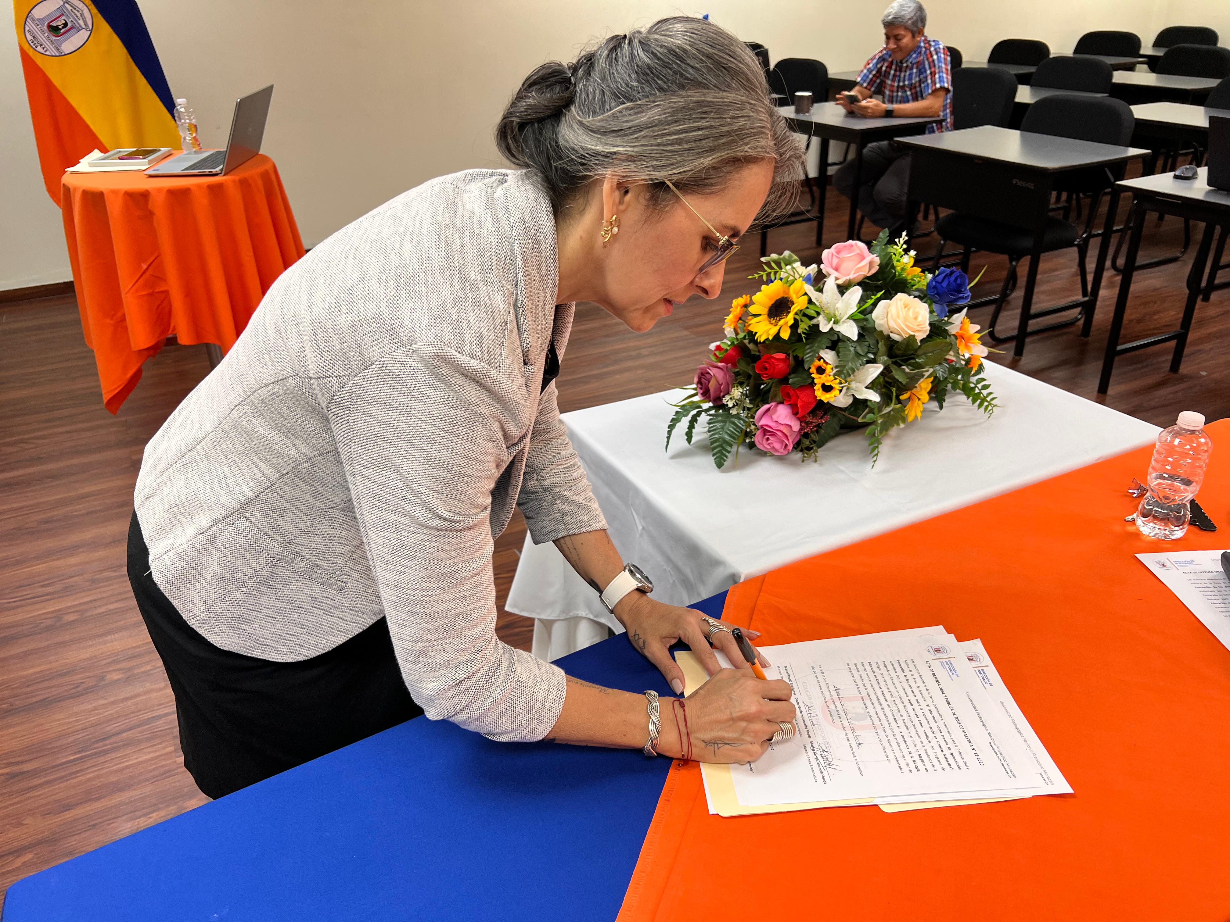 La Licda. Loyda Adriana Zerón Henríquez firmando las actas de defensa oral y pública.